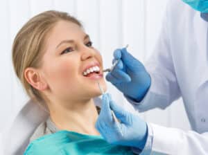 Young woman in dentist’s office happy to be getting a root canal for her tooth pain.